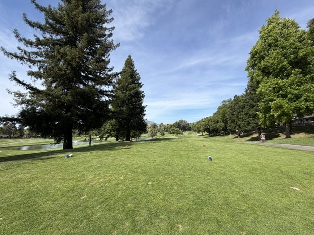 Tree-lined fairway at Crow Canyon Country Club with a pond and the Diablo foothills beyond